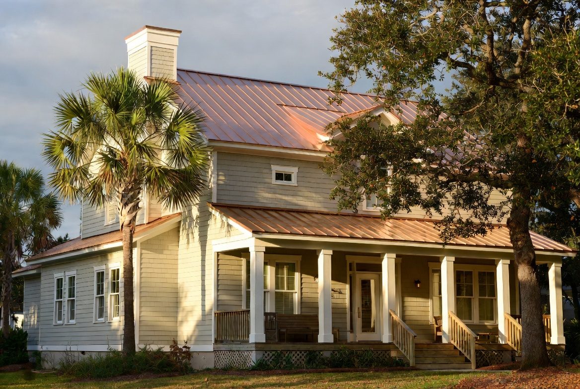 Coastal home with copper standing-seam metal roof at golden hour